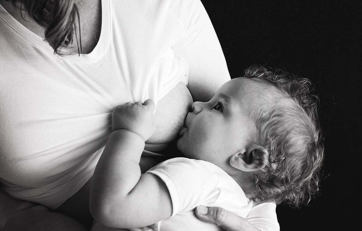 Black and white photo of a child being breastfed