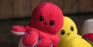 Red and yellow octopus plushes. The red one has an angry expression while the yellow one has an happy expression.
