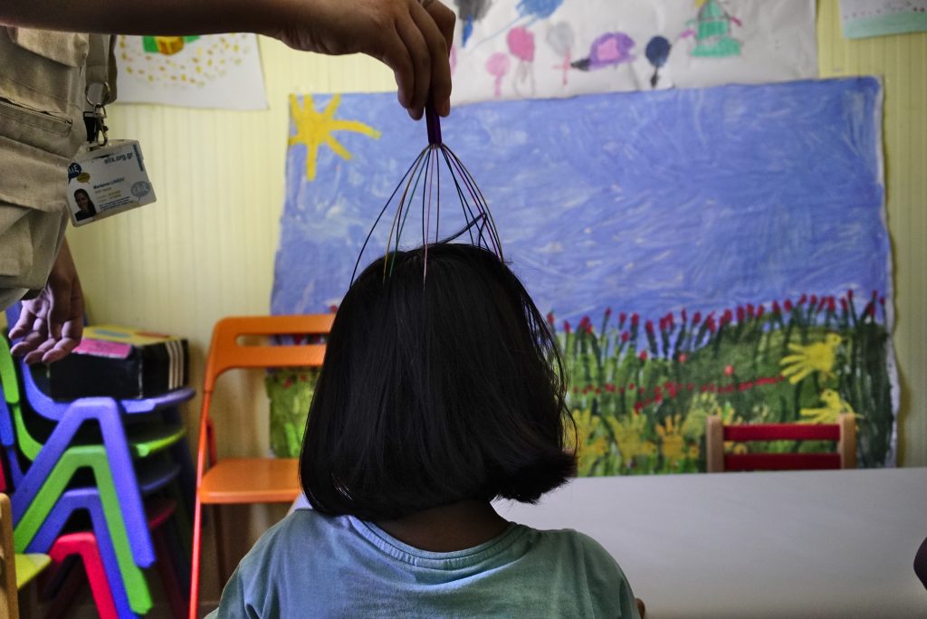 The head of a child, seen from behind, being massaged with a scalp massager.